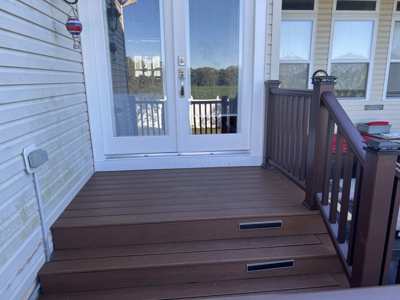 Finished composite deck landing and steps outside a patio door